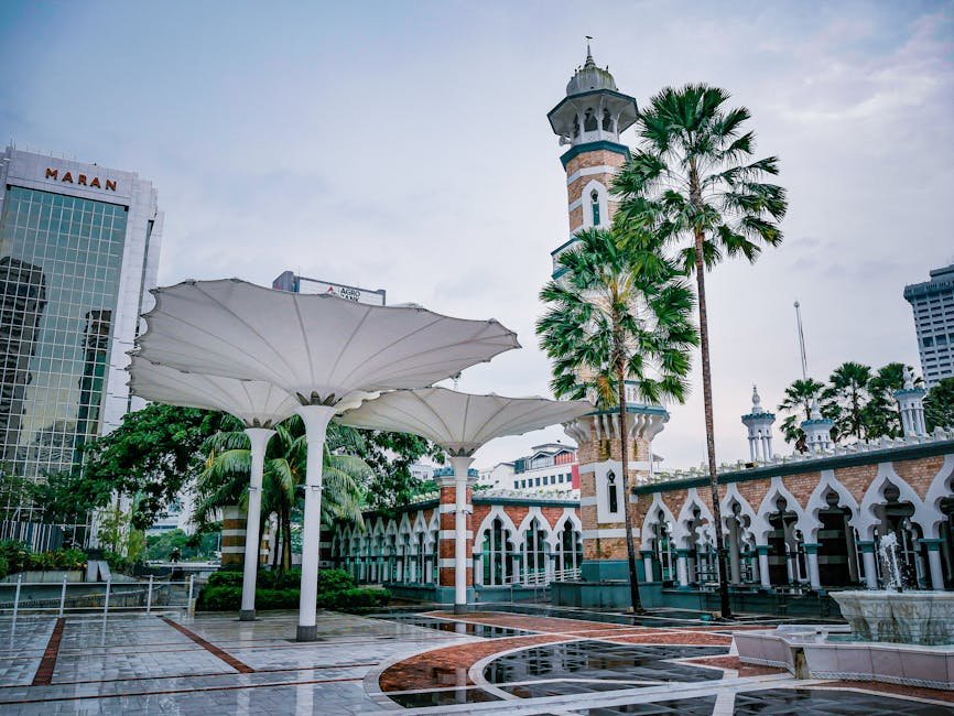 View of Jamek Mosque with lush palm trees and modern architectural elements in Kuala Lumpur, Malaysia.