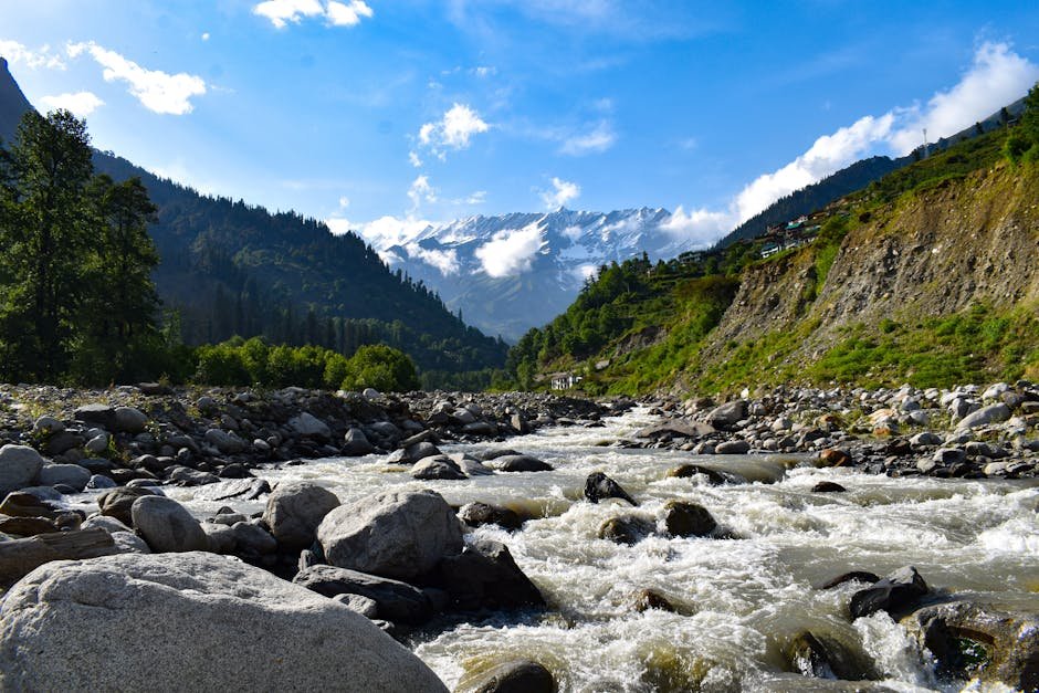 Flowing river through rocks with mountain backdrop in Manali, India