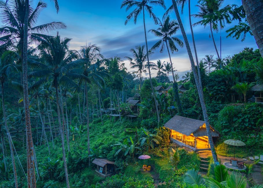 A serene tropical hut illuminated at twilight in a lush Balinese forest setting, surrounded by tall palm trees.